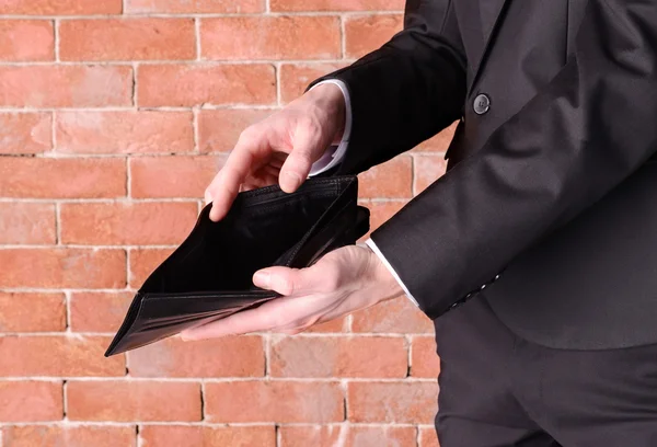 Man in a suit showing an empty purse