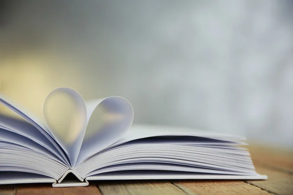 Sheets of book curved into heart shape on unfocused background