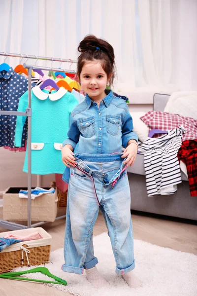 Little girl in the room with a lot of clothes