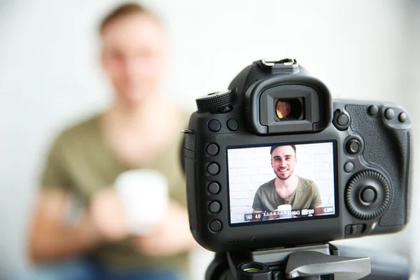 Young male blogger on camera screen