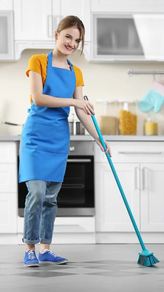 Young woman washing floor in kitchen