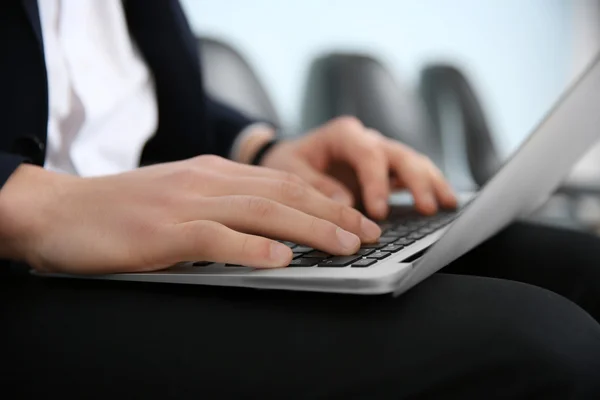 Man in suit sitting on chair with laptop