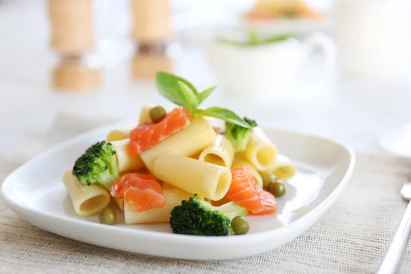 Boiled rigatoni pasta with salmon and broccoli on white plate