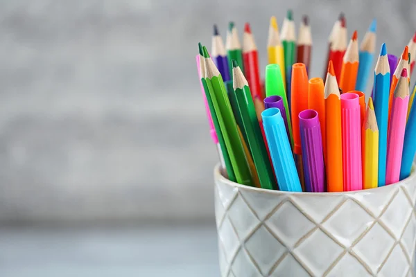 Pencils and markers in ceramic cup