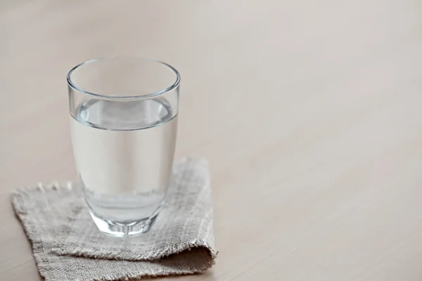 Glass of pure water on light wooden table