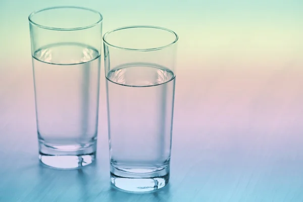 Two glasses of pure water on light wooden table