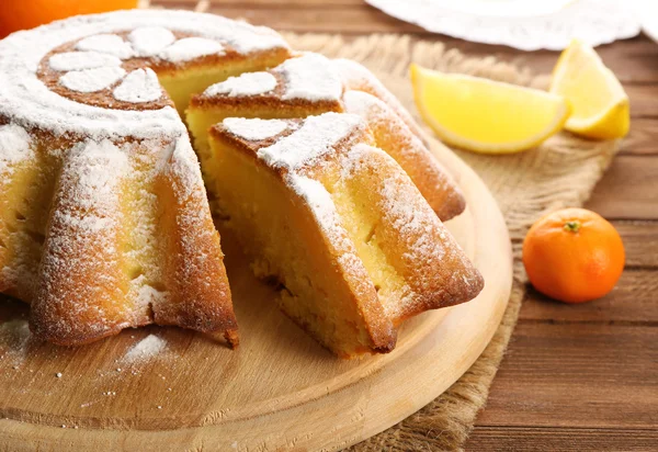 Delicious citrus cake with fruits on wooden board