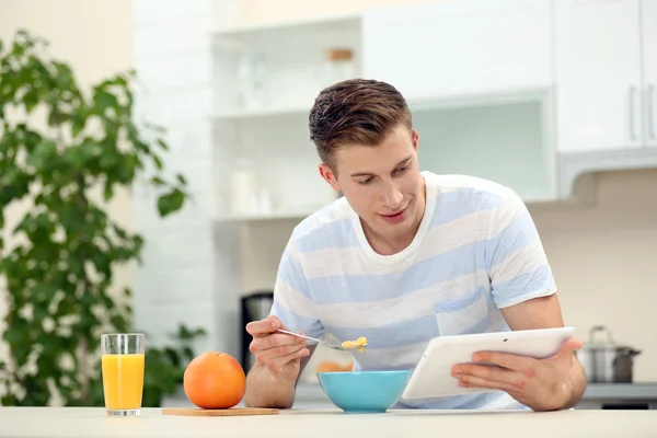 Man with tablet and having breakfast