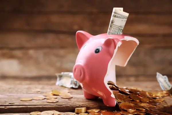 Broken piggy bank with cash and coins