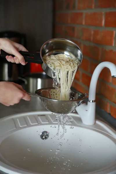 Pouring water from boiled spaghetti