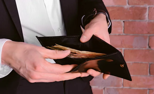 Man in a suit showing a purse with banknotes