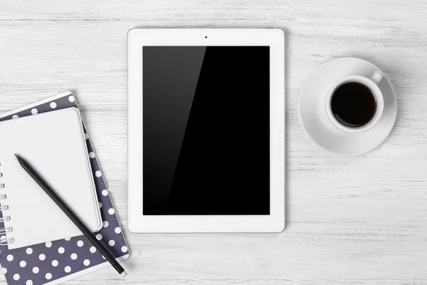 Digital tablet with cup of coffee and notebook