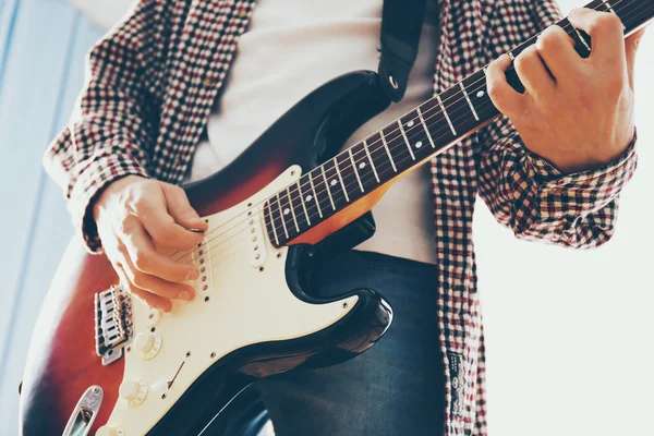 Young man plays electric guitar