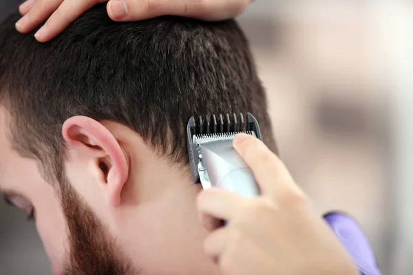 Hairdresser cutting hair with hair clipper