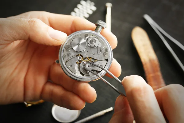 Watchmaker hands repairing old watch