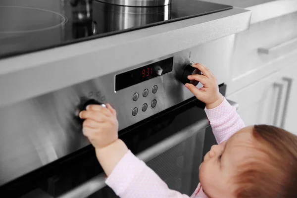 Little child playing with electric stove