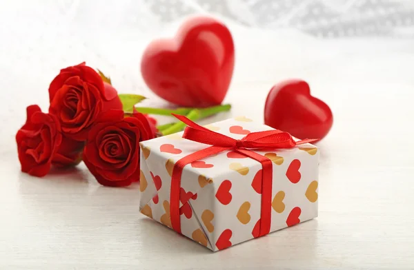Gift box, rose flowers and decorative hearts