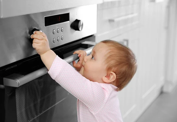 Little child playing with electric stove