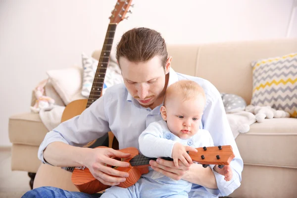 Father playing guitar to son