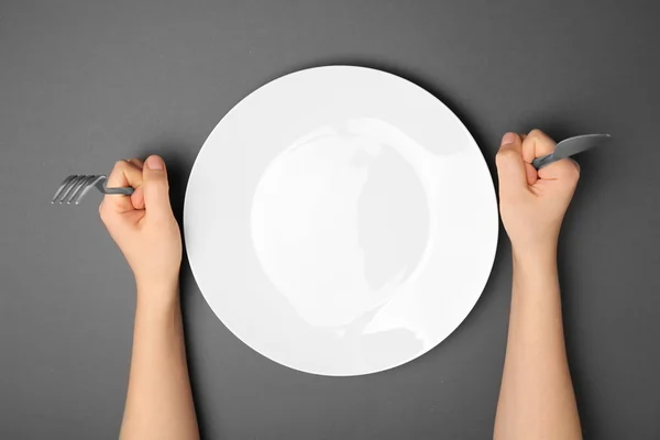 Female hands with cutlery and empty plate