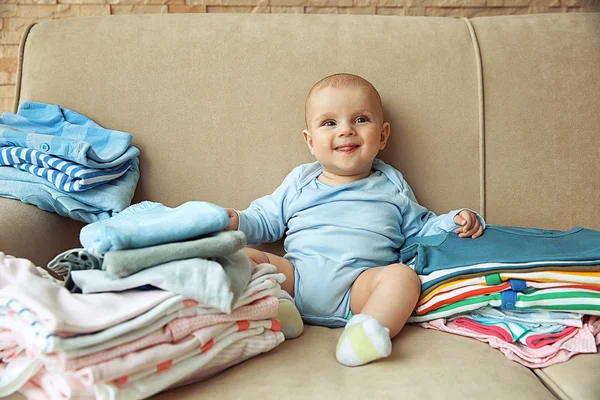 Adorable baby with piles of clothes