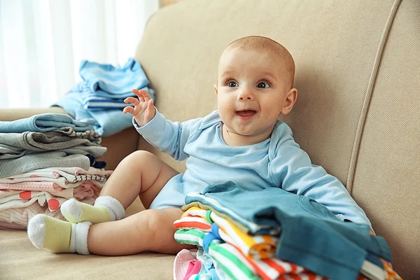 Adorable baby with piles of clothes