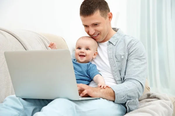 Father holding baby and working