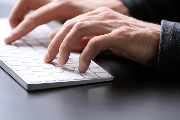 Male hands typing on wireless keyboard
