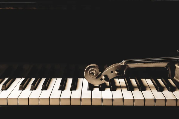 Violin neck lying on piano keys, close up