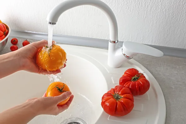 Female hands washing tomatoes