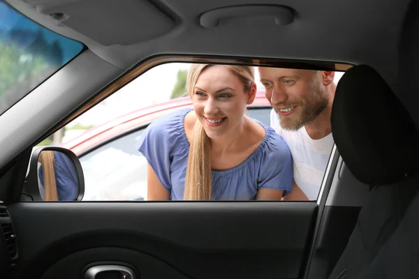 Young couple looking inside car