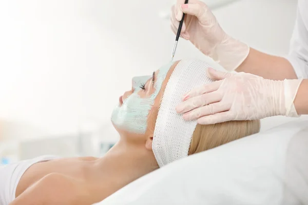 Cosmetologist applying facial mask