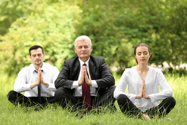 Business people relaxing in meditation pose