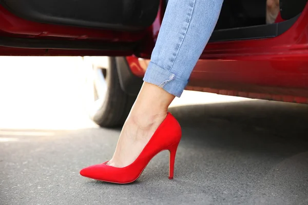 Female leg in red shoe from opened car door