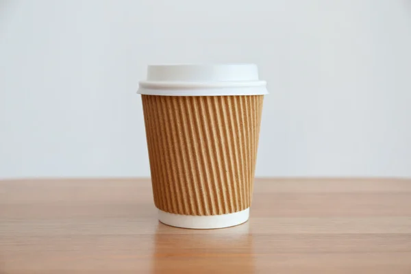 Paper cup of coffee on light background