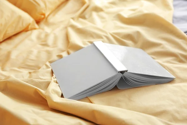Open upside book on crumpled bed