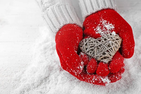 Hands in warm red gloves holding wicker heart