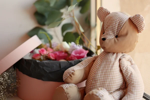 Box with fresh flowers and teddy bear