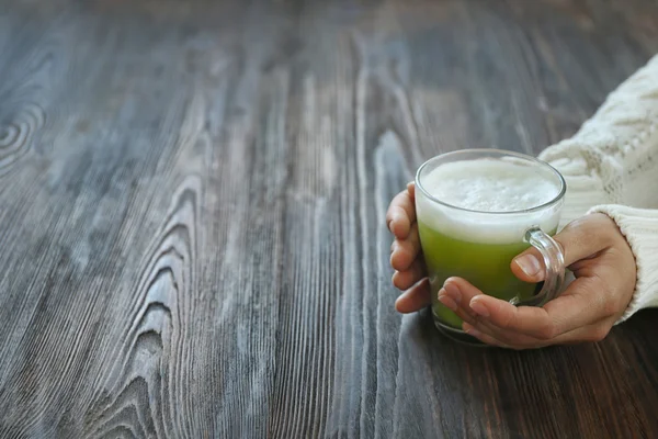 Hands holding cup of green matcha tea