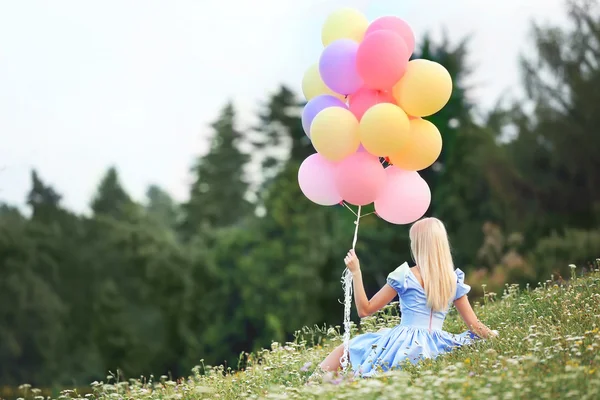 Beautiful young woman holding air balloons