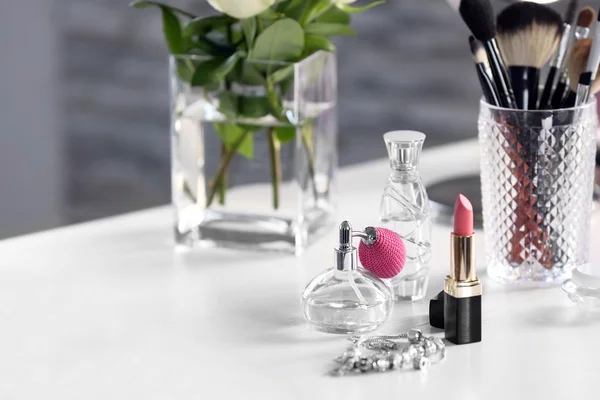 Perfume bottle with lipstick on light dressing table