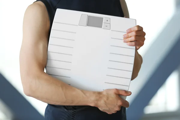 Man holding weight scale, close up