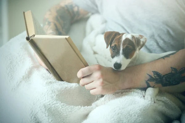 Man with cute dog reading book