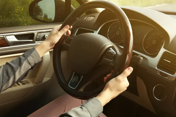 Female hands on driving wheel