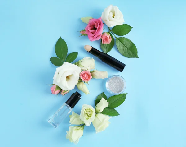 Cosmetics and flowers on blue