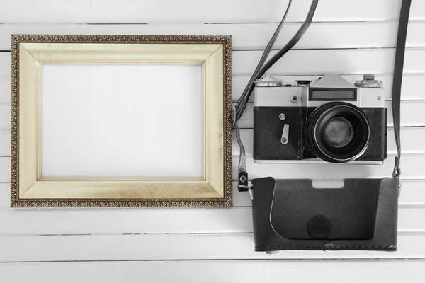 Vintage camera and frame on white wooden background