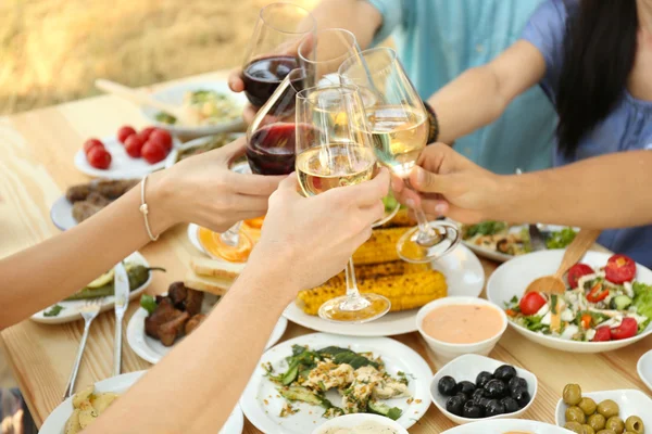 Friends cheering with glasses of wine on picnic