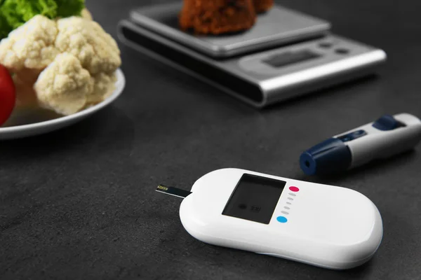 Glucose meter with vegetables and cookies on table