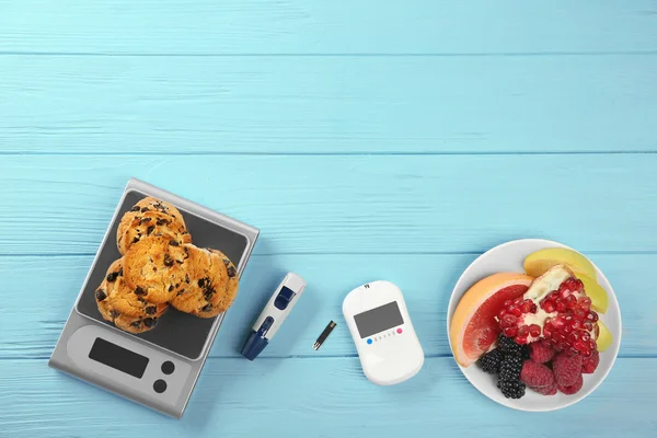 Glucose meter with fruits and cookies on table