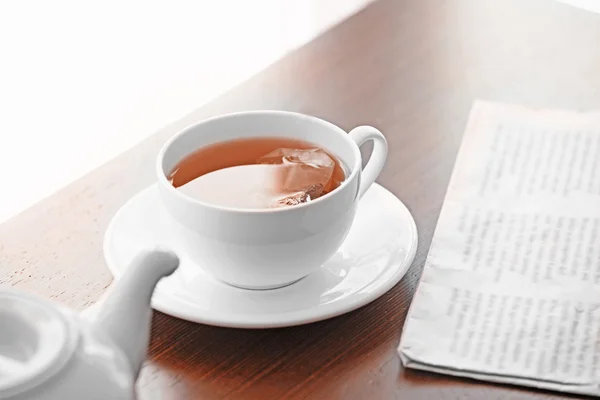 Cup of tea with newspaper on table